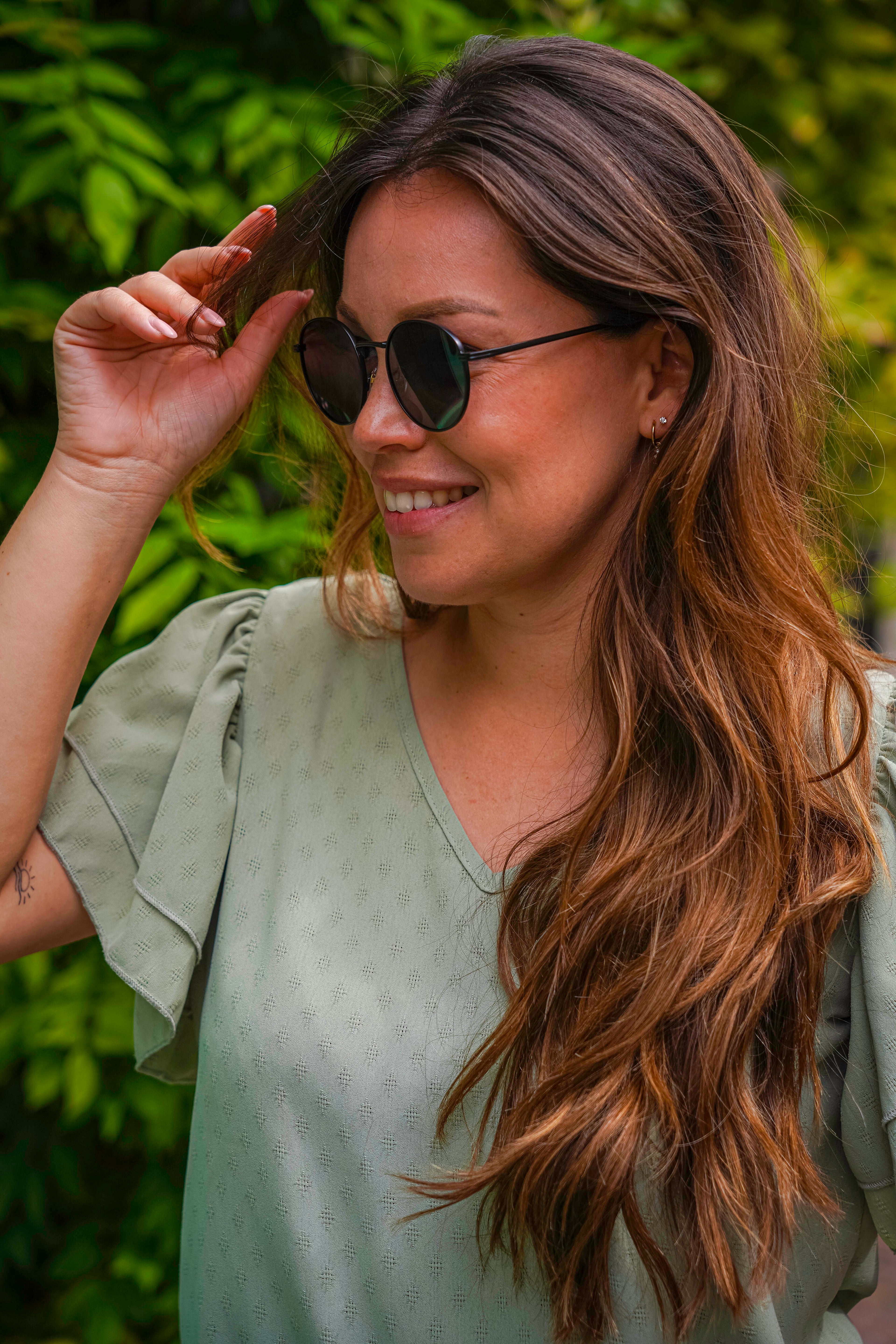 Vrouw met stijlvolle zonnebril in groene natuur, perfect voor zomerse dagen