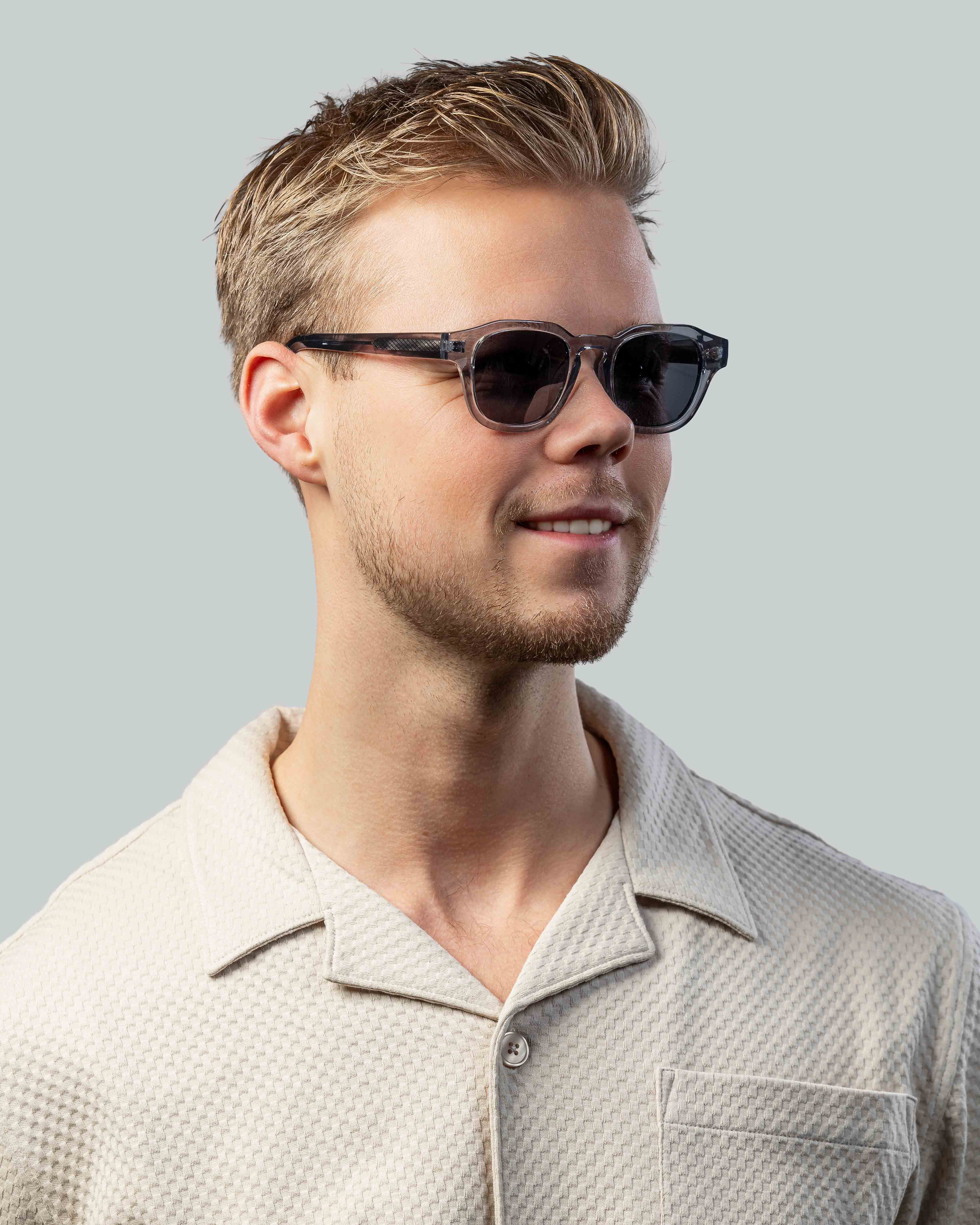 Stijlvolle zonnebril voor mannen met donkere glazen en transparante montuur, perfect voor een moderne look.
